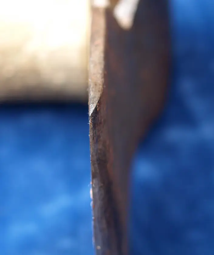 Close-up of a side axe blade, bevelled on one side and flat on the other